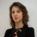 Headshot of Lorena, a young woman with swept back brown hair wearing a black blazer