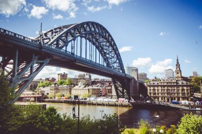 The Tyne Bridge, a large blue steel arch bridge, spanning the River Tyne in Newcastle, UK.
